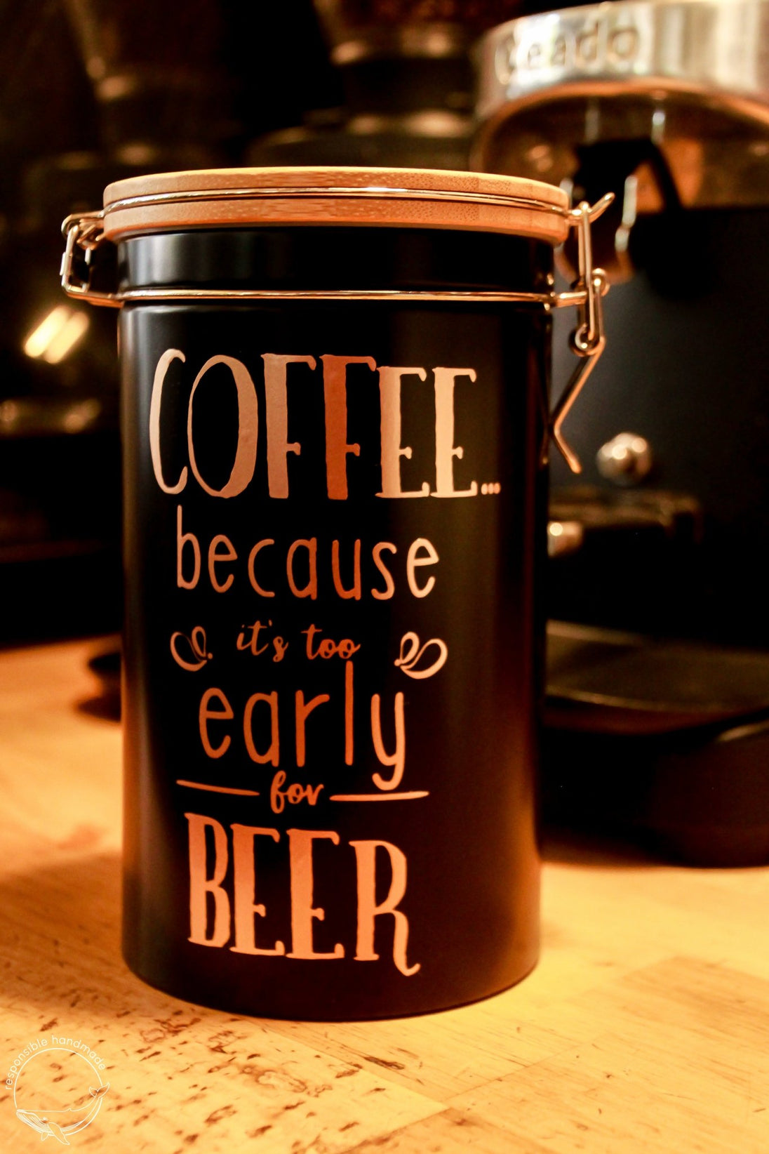Schwarze Kaffeedose mit Bambusdeckel und Bügelverschluss in Kaffeebar, rosegoldener Spruch: COFFEE because it´s