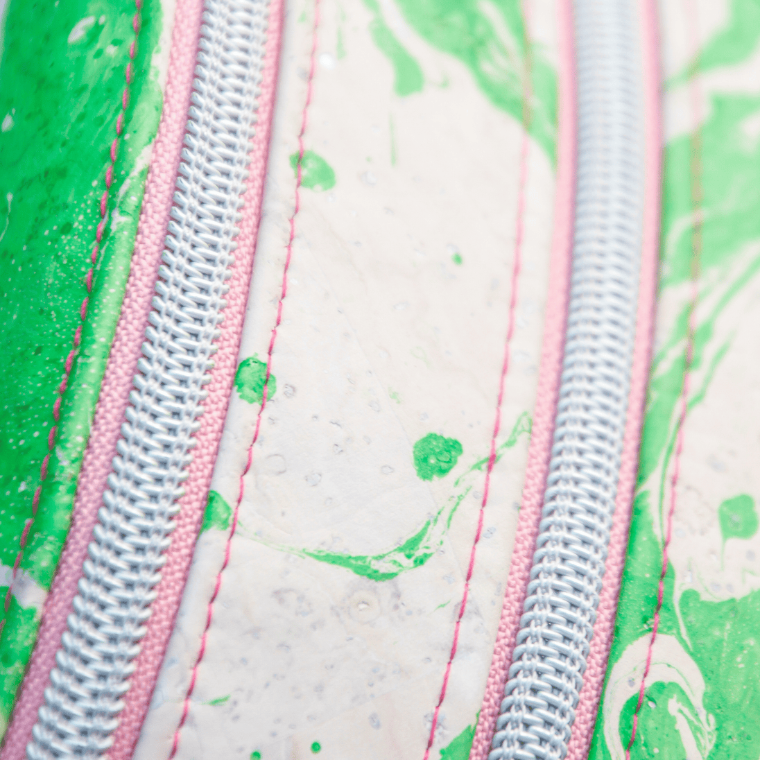 Detailbild der rosefarbenden Reißverschlüsse von Slingbag in grün/weiß